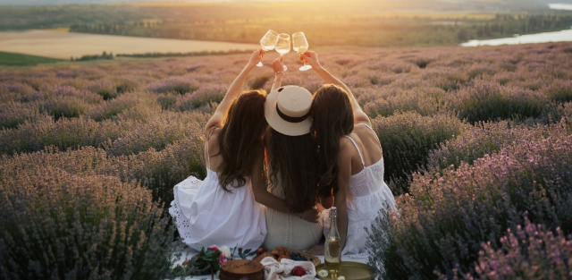 세 명의 여자가 야외에서 와인잔을 들고 짠 하는 사진